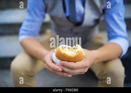 Deatil der moderne Hipster Geschäftsmann, die Mittagspause, sitzt auf der Treppe in der Stadtmitte und Burger Essen Stockfoto