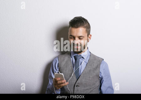 Studioaufnahme der moderne Hipster Geschäftsmann mit Kopfhörer, Musik vom Handy hören Stockfoto