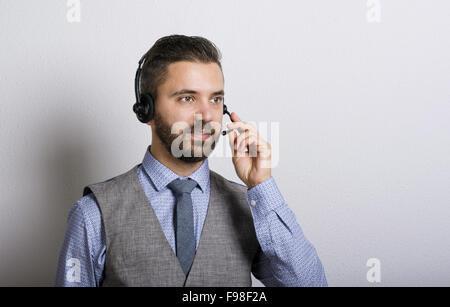 Call Center-Betreiber isoliert auf weiss. Junge hübsche Hipster Mann mit Kopfhörer. Stockfoto