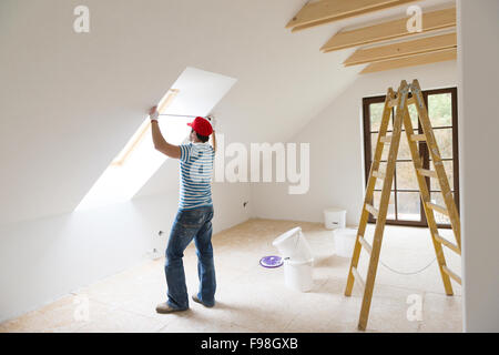 Junger Mann, die Messung der Wand des neuen Heims mit Maßband Stockfoto