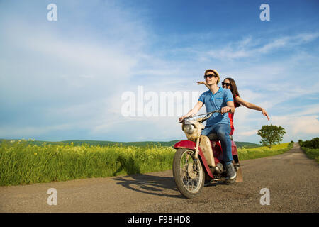 Glückliches junges Paar in Liebe auf Retro-Motorrad fahren Togetger und Ejoying die Reise im grünen Bereich Stockfoto