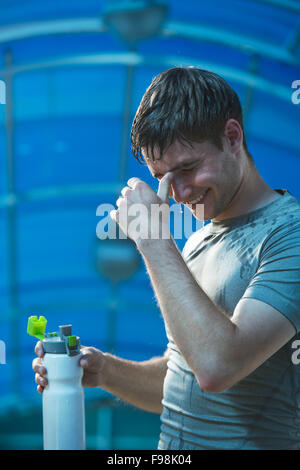 Mann Fitness Läufer trinken und Spritzwasser in seinem Gesicht. Lustiges Bild gut aussehend männlichen erfrischende während des Trainings Stockfoto