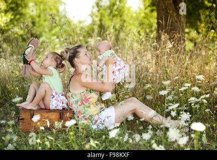 Glückliche junge Mutter verbringt Zeit mit ihren kleinen Töchtern in der grünen Natur. Stockfoto