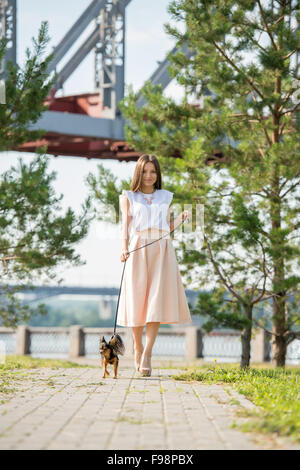 Junge schöne Frau zu Fuß mit ihrem Hund an der Leine im Sommerpark Stockfoto