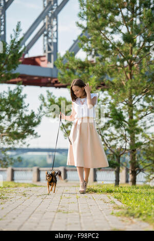 Junge schöne Frau zu Fuß mit ihrem Hund an der Leine im Sommerpark Stockfoto