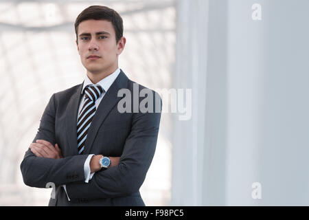Porträt der schönen zuversichtlich junger Geschäftsmann stehend Arme verschränkt, lächelt glücklich, Blick in die Kamera. Stockfoto