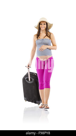 Schöne schwangere Frau in Sommerkleidung und Strohhut bereit zu reisen, isoliert auf weiss Stockfoto