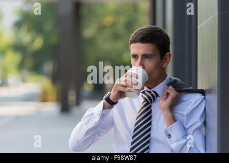 Porträt eines schönen Geschäftsmann Kaffeetrinken auf der Straße in der Nähe von Bürogebäude Stockfoto