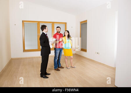 Junges Paar sitzt auf dem Boden in ihren leeren neuen Haus. Frau ist schwanger. Stockfoto