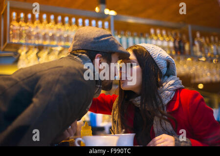 Junges Paar in Winterkleidung küssen im café Stockfoto