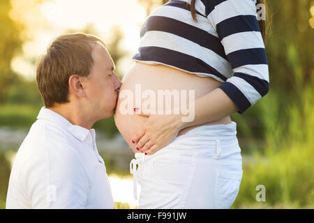 Mann ist in der Natur schwangere Frau Bauch küssen. Stockfoto