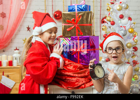 Zwei Mädchen Schwestern, vier und sechs Jahren in das neue Jahr Kostüme sind an der Tasche mit Weihnachtsgeschenken Stockfoto