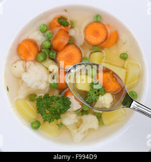 Gesundes Essen Gemüsesuppe mit Gemüse, Kartoffeln, Karotten und Erbsen auf Löffel von oben Stockfoto