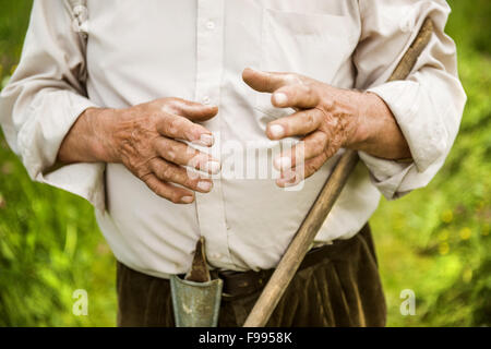Alter Bauer mit Bart mit Rechen im Garten arbeiten Stockfoto