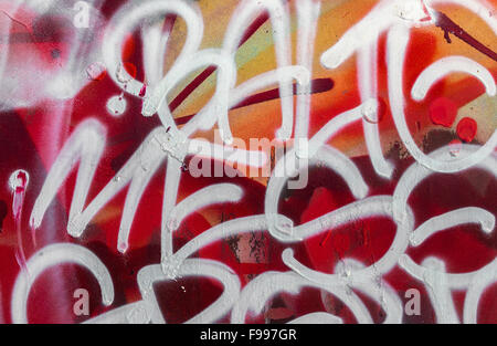 Graffiti an der Wand aus weißer Schrift auf rot und orange Hintergrund. Stockfoto