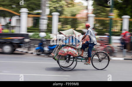 YOGJAKARTA, Indonesien - 21. August 2015: panning Shot Leute Reiten in einem Becak durch die Straßen von Yogyakarta. Stockfoto