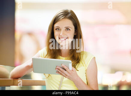 Hübsches junges Mädchen in einem Einkaufszentrum und mit ihrem tablet Stockfoto