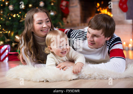 Glückliche junge Eltern und Kind viel Spaß in der Nähe von Weihnachtsbaum zu Hause.  Vater, Mutter und Sohn gemeinsam feiern Neujahr Stockfoto