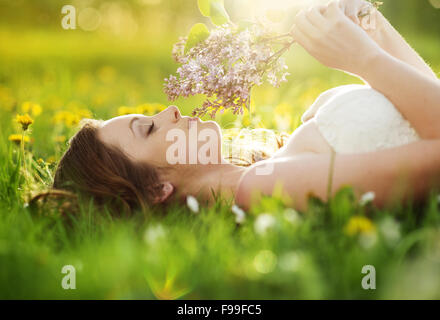 Schönes Mädchen ist entspannend liegen auf dem Rasen im Garten Stockfoto