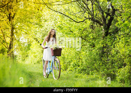 Hübsche junge Frau Reiten Retro-Motorrad im grünen park Stockfoto