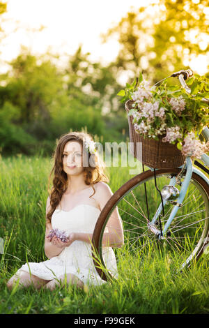 Hübsche junge Frau mit Retro-Motorrad im grünen park Stockfoto