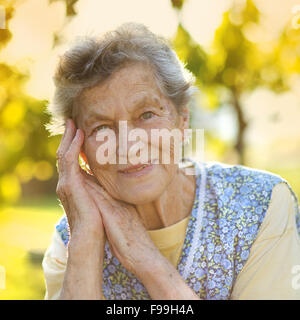 Porträt von senior Frau in Schürze im sonnigen Garten Stockfoto