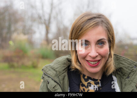 Porträt einer lächelnden jungen Frau schaut in die Kamera, mit blauen Augen und blonden Haaren. Tageslicht, natürliche Hautpflege, ausgeschossen Stockfoto