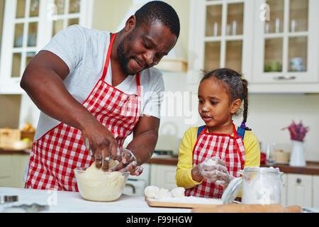 Junger Mann und seine Tochter machen Gebäck in der Küche Stockfoto