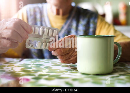 Nahaufnahme des alten Weibes Hände halten Pillen in Küche Küche Stockfoto