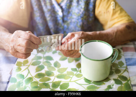 Nahaufnahme des alten Weibes Hände halten Pillen in Küche Küche Stockfoto