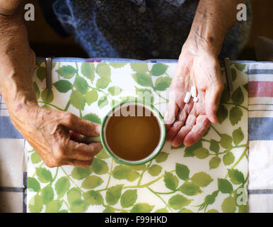 Nahaufnahme des alten Weibes Hände halten Pillen in Küche Küche Stockfoto