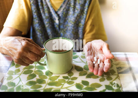 Nahaufnahme des alten Weibes Hände halten Pillen in Küche Küche Stockfoto