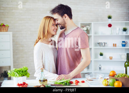 Glückliches junges Paar tatenlos Tisch mit vegs in der Küche Stockfoto