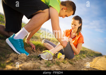 Verletzungen - Sport Frau mit verletzten Knie Hilfe von Mann ihr Knie berühren. Stockfoto