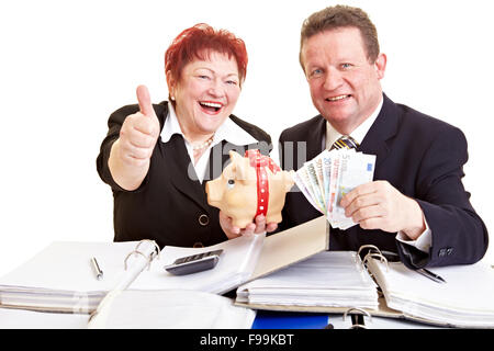 Zwei ältere Menschen halten europäisches Geld und ein Sparschwein Stockfoto