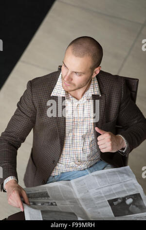 Gut aussehend Unternehmer oder Manager in Bürogebäude lesen Zeitung Blick von oben Stockfoto