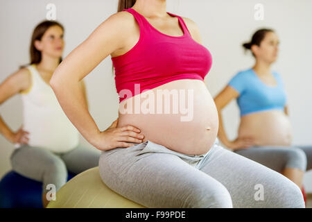 Junge schwangere Frauen tun Übung mit einem Fitnessball Stockfoto