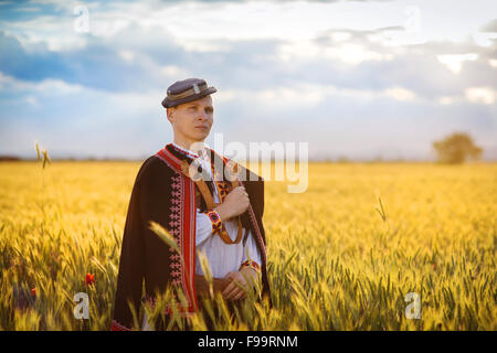 Mann im Feld Sonnenuntergang. Er ist Osteuropa Trachten tragen. Stockfoto