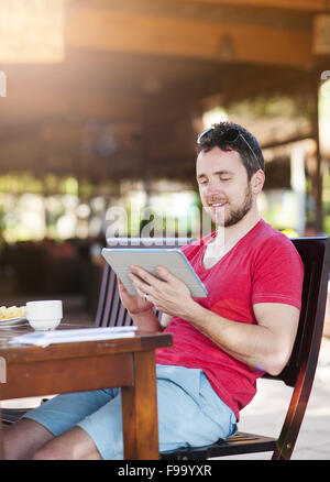 Hübscher Jüngling, entspannend und mit digital-Tablette Stockfoto