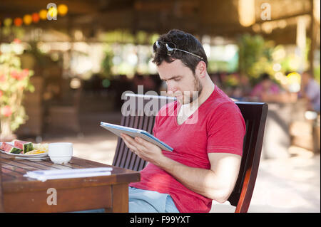 Hübscher Jüngling, entspannend und mit digital-Tablette Stockfoto