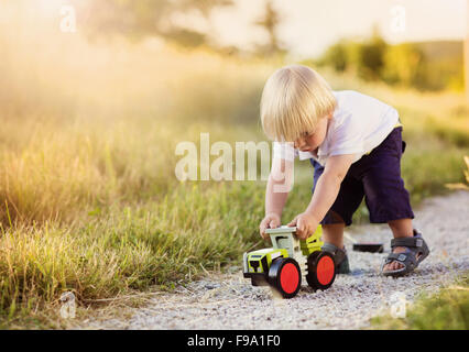 Kleiner Junge spielt mit Spielzeug-Traktor Landschaft unterwegs Stockfoto