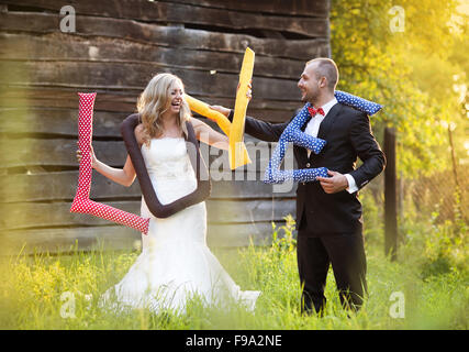 Glückliche Braut und Bräutigam am Tag ihrer Hochzeit Spaß mit Liebe Kissen draußen im Garten Stockfoto