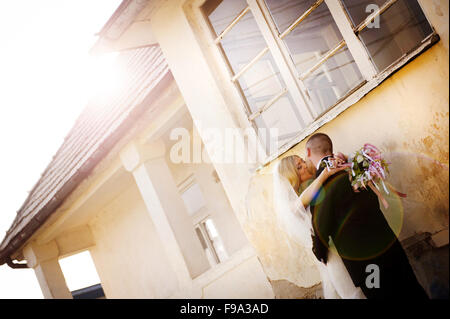 Glückliche Braut und Bräutigam posieren durch das alte Haus Stockfoto