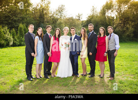 In voller Länge Portrait von Brautpaar posiert mit Brautjungfern und Trauzeugen in sonnigen, grünen park Stockfoto