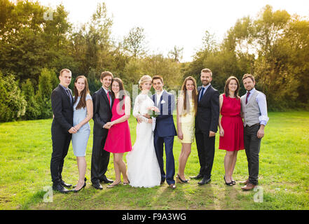 In voller Länge Portrait von Brautpaar posiert mit Brautjungfern und Trauzeugen in sonnigen, grünen park Stockfoto