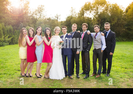 In voller Länge Portrait von Brautpaar posiert mit Brautjungfern und Trauzeugen in sonnigen, grünen park Stockfoto