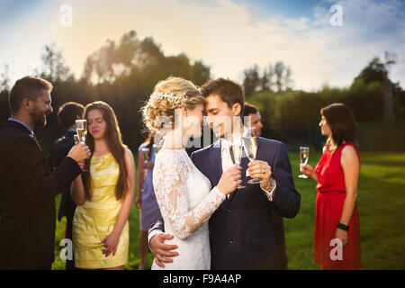 Junge Brautpaar Gläser klirren und genießen romantische Momente zusammen auf Hochzeit außerhalb Stockfoto