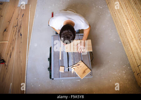 Erhöhte Ansicht der Handwerker schneiden Sperrholz an Kreissäge im neuen Haus Stockfoto