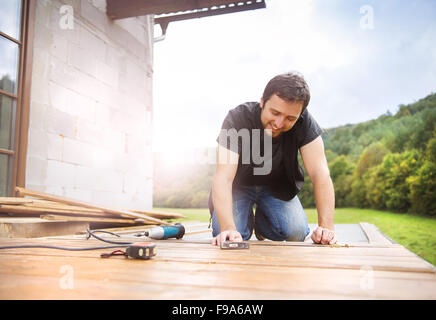 Lächelnd Handwerker installieren Holzböden im Patio, arbeiten mit hammer Stockfoto