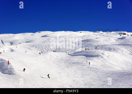 Breiten Bereich der Ski Pisten mit vielen abgerundeten Hügel und Skifahrer, die überall verteilt. Weißer Schnee und klarer blauer Himmel nur. Stockfoto